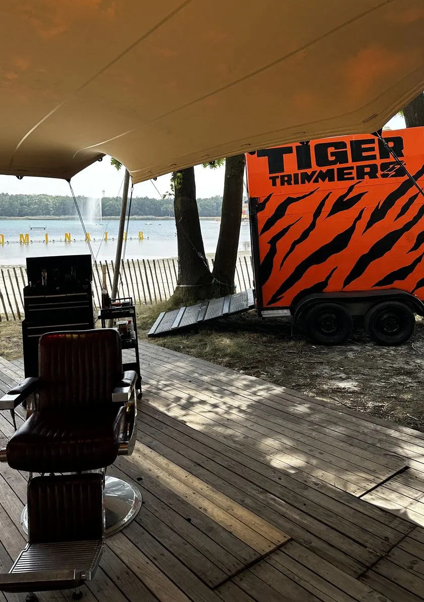 De Tiger Trimmers kapperstrailer met tijgerprint op locatie aan het water.